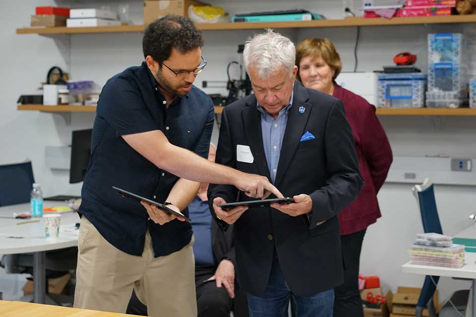 A faculty member presents a device in a lab.