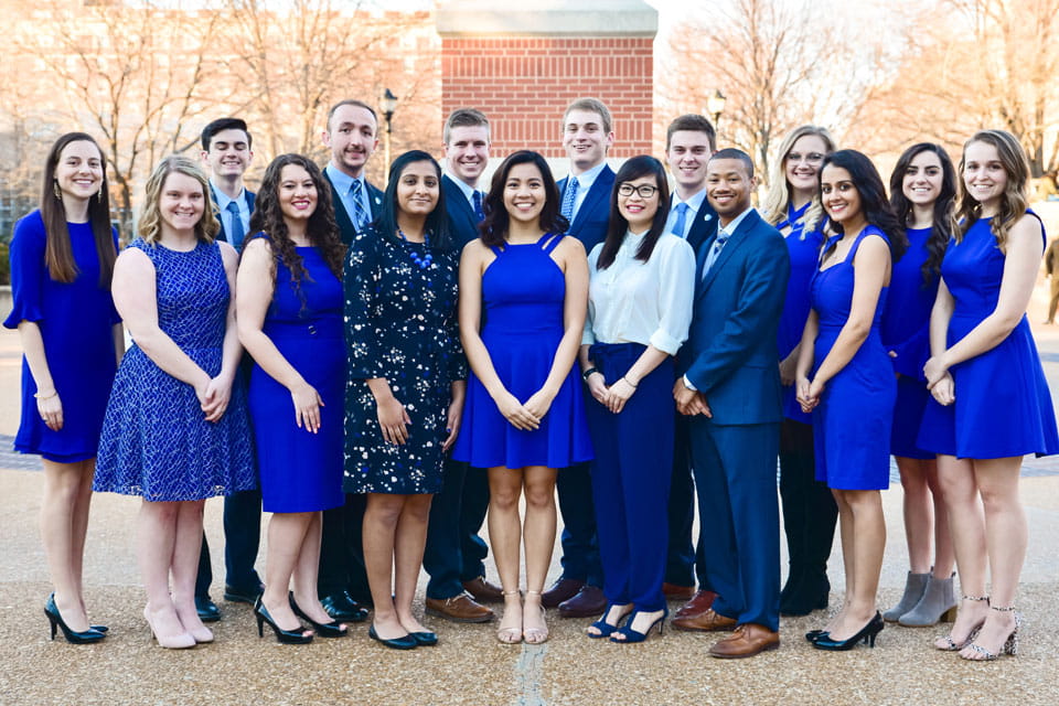 A group of students pose for a photo outside on campus.