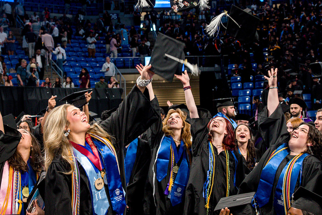 A group of women throw their graduation caps