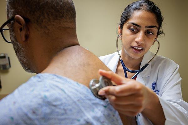 Medical students examine a standardized patient.