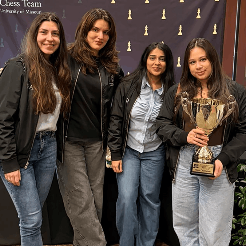 Four students pose with a trophy.