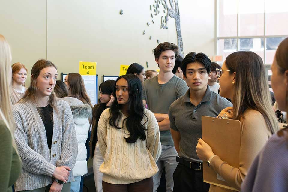 A group of college students presents a posterboard with student research findings