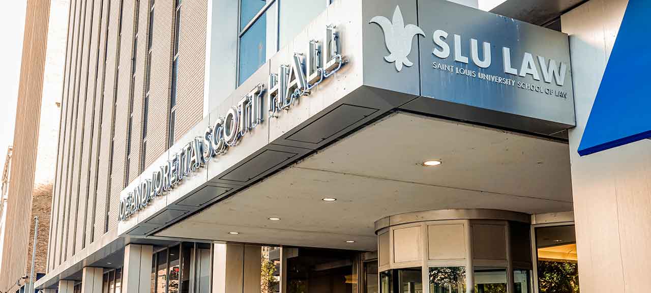 An exterior view of Scott Hall, including the front facade that reads Joe and Loretta Scott Hall. Students can be seen entering and exiting the building.