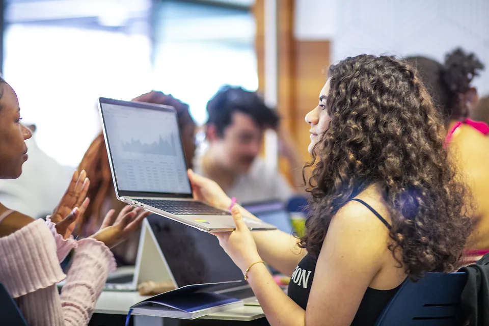 Two students sharing the information on a laptop screen.