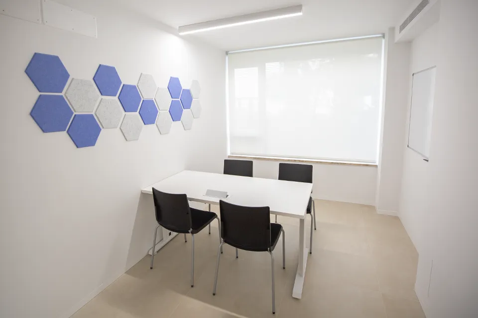 A lighted white room with a table and four chairs.