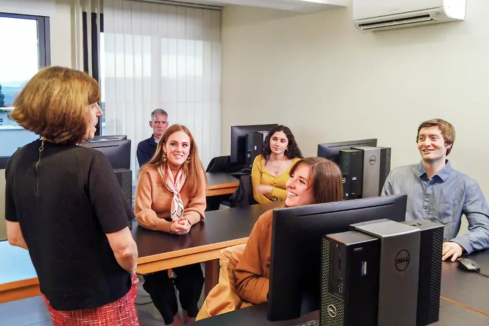 A group of students sitting at a table attending to the professor.