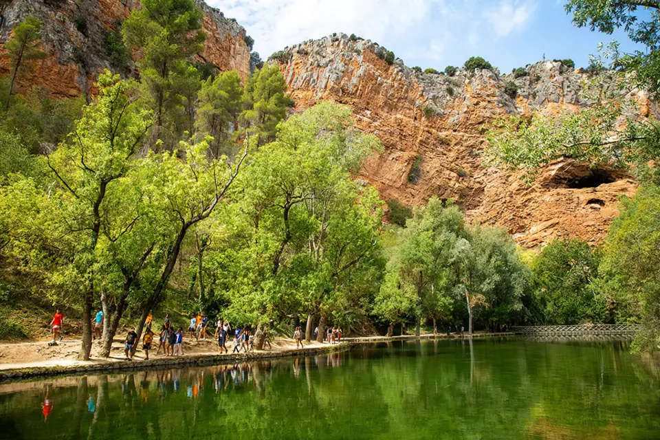 People walking along a river between mountains.