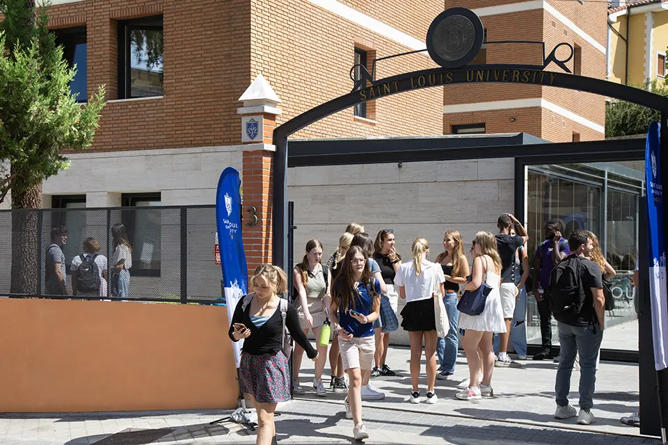 Students walk through and stand and talk in an outdoor area of the SLU Madrid campus.