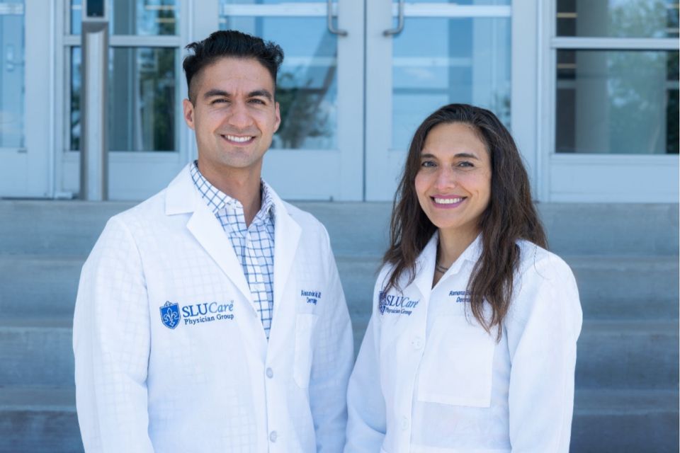 Two faculty members pose outdoors.