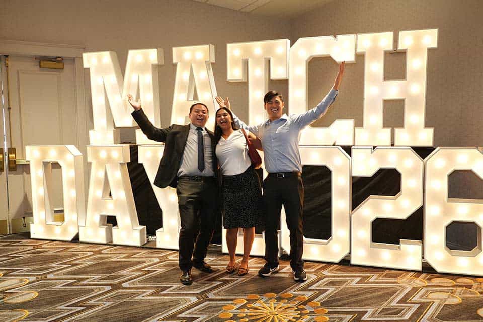 SLU medical students celebrate in front of a "Match Day 2026" illuminated sign