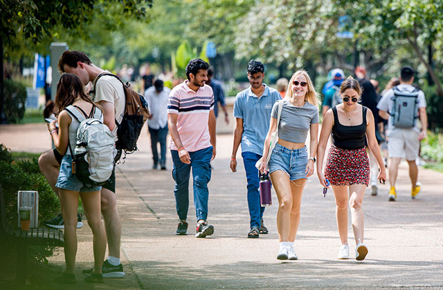 Two students walking together down a crowded pedestrian mall Two students walking together down a crowded pedestrian mall