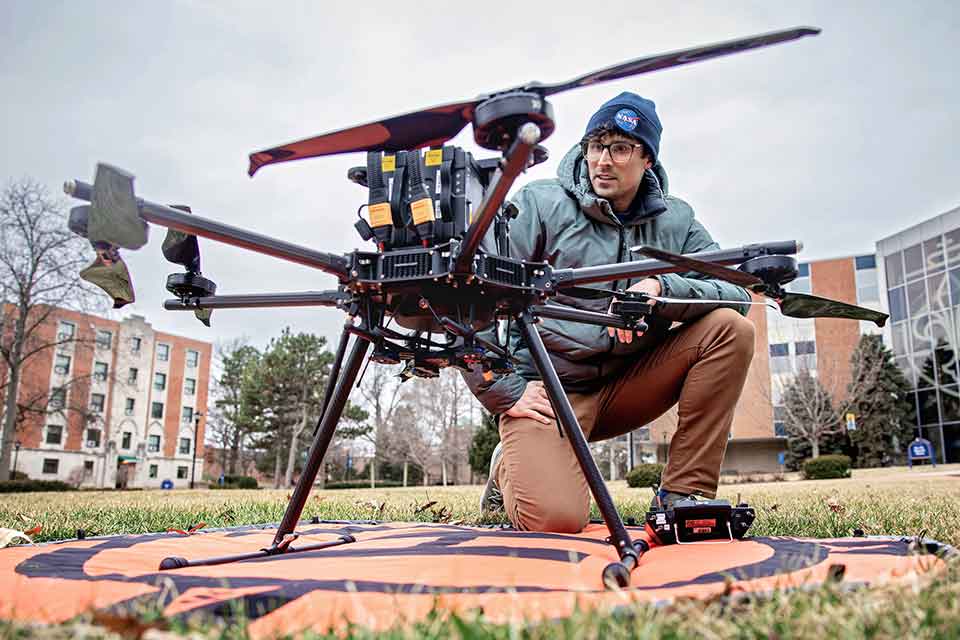 A man examines a large drone on SLU's campus