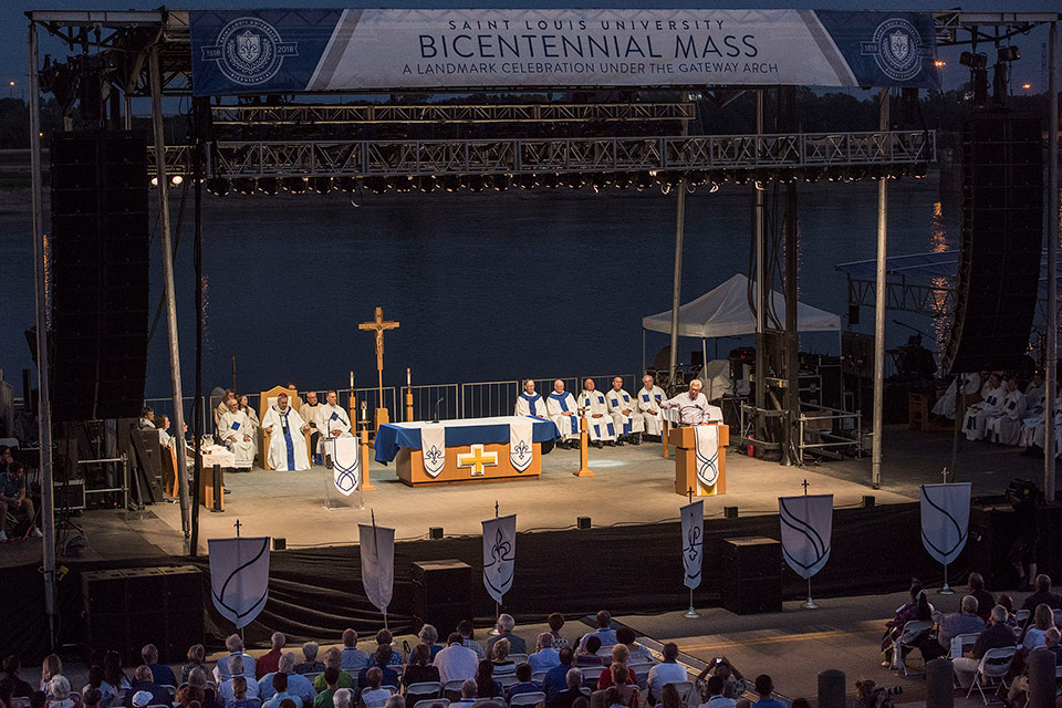 Pestello on stage, at a podium, addresses a crowd of 6,000 following the Bicentennial Mass under the Gateway Arch.